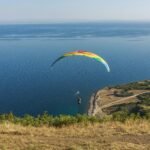 a paraglider is flying over a body of water